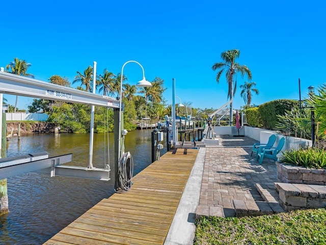 dock area with a patio, a water view, and boat lift