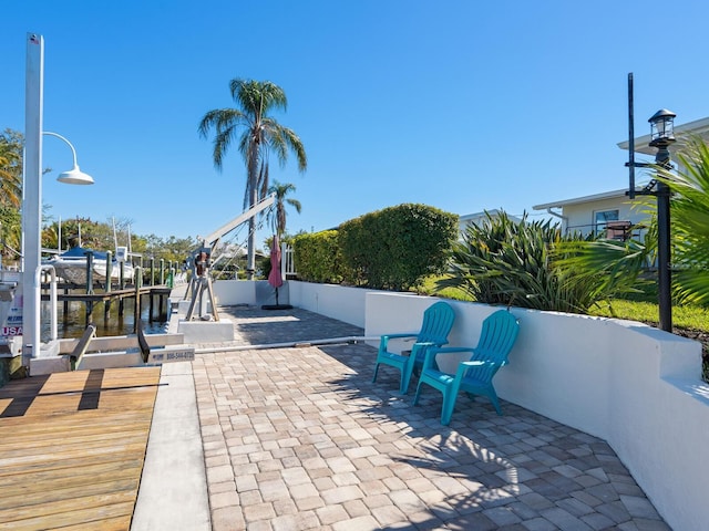 view of home's community featuring a water view, a boat dock, and a patio