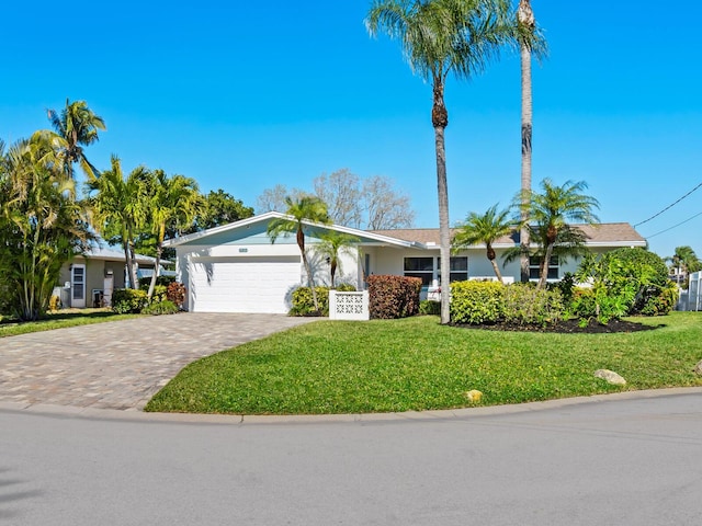 ranch-style home featuring a front yard, an attached garage, driveway, and stucco siding