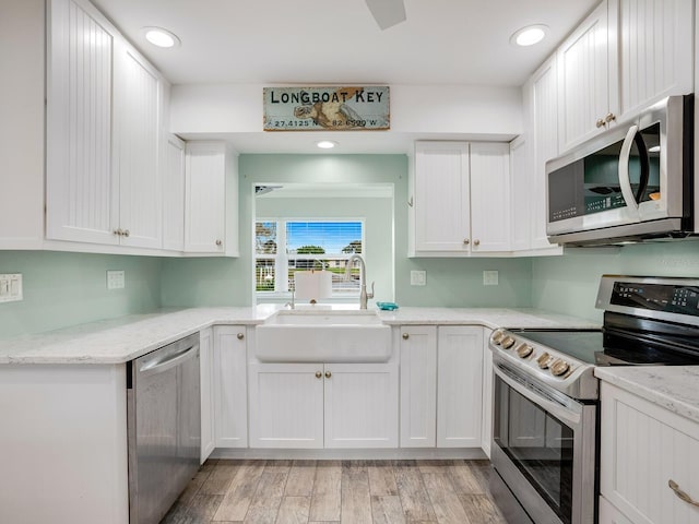 5303 Coral Blvd, Bradenton, FL 34210 - kitchen with a sink, white cabinetry, stainless steel appliances, light wood finished floors, and light stone countertops