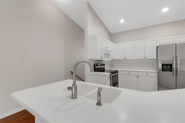 kitchen featuring appliances with stainless steel finishes, white cabinetry, sink, dark hardwood / wood-style flooring, and kitchen peninsula