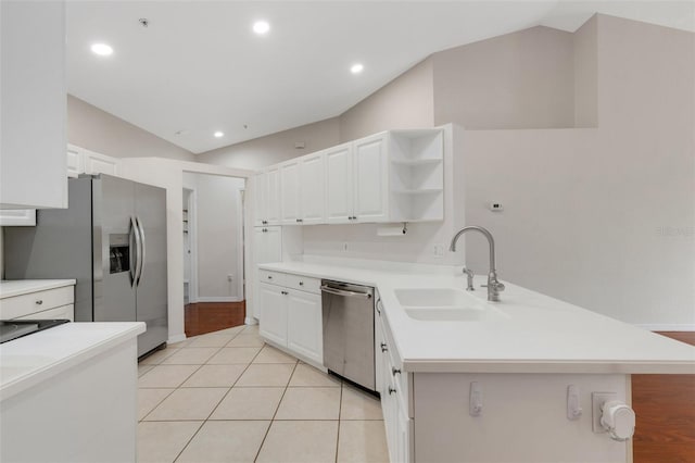 kitchen featuring vaulted ceiling, appliances with stainless steel finishes, sink, white cabinets, and kitchen peninsula