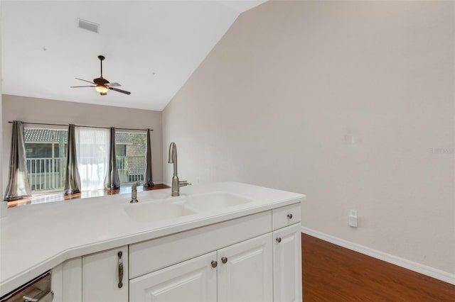 kitchen featuring dark hardwood / wood-style floors, dishwasher, lofted ceiling, sink, and white cabinets