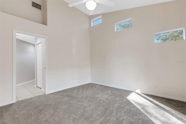 spare room featuring ceiling fan, light carpet, and high vaulted ceiling