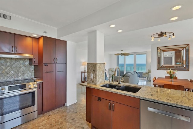 kitchen with appliances with stainless steel finishes, sink, decorative backsplash, a water view, and light stone countertops