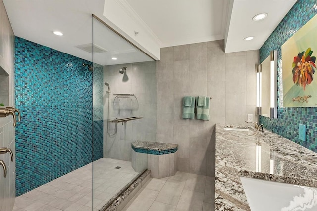 bathroom with a tile shower, tasteful backsplash, tile walls, vanity, and ornamental molding