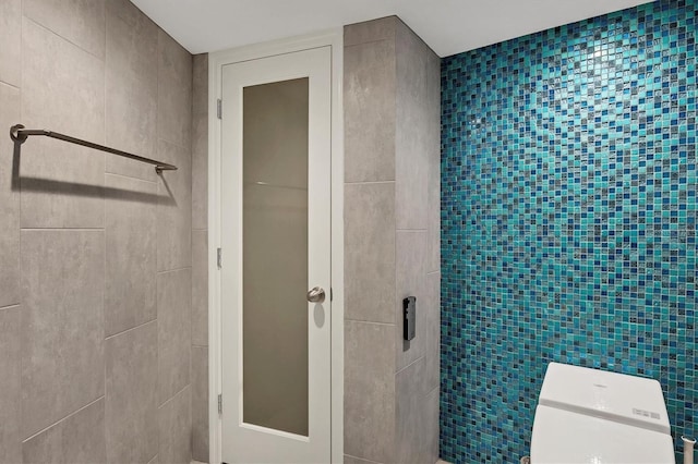 bathroom with toilet and tile walls