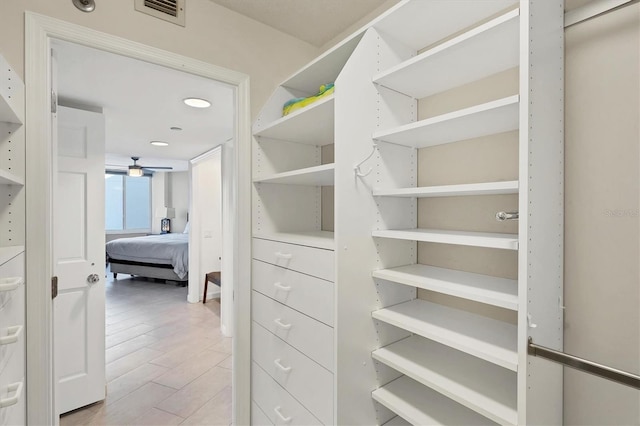 walk in closet featuring light hardwood / wood-style flooring and ceiling fan