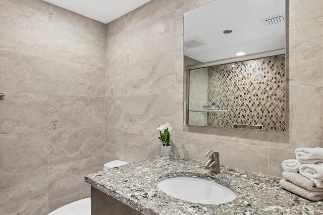 bathroom featuring decorative backsplash, vanity, toilet, and tile walls