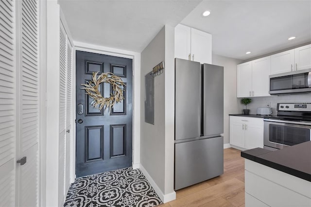 kitchen featuring white cabinetry, stainless steel appliances, light hardwood / wood-style flooring, and backsplash