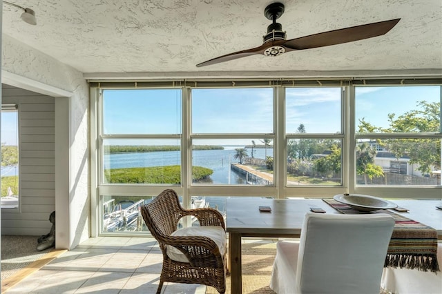 sunroom with a water view, a healthy amount of sunlight, and ceiling fan