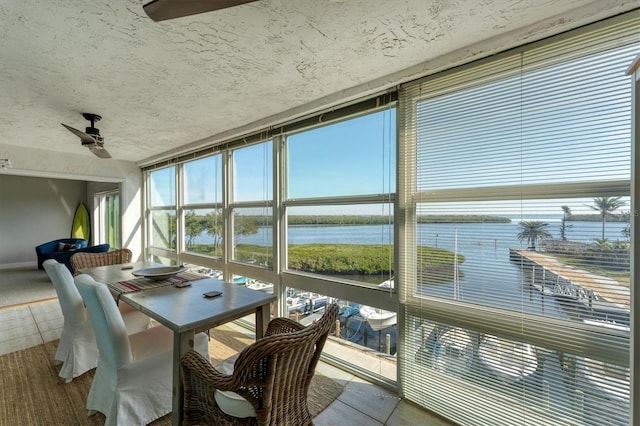 sunroom / solarium featuring a water view and ceiling fan