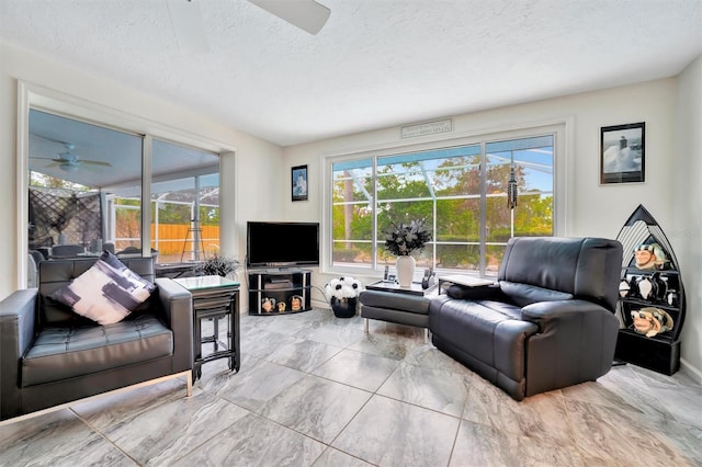 living room featuring ceiling fan and a textured ceiling