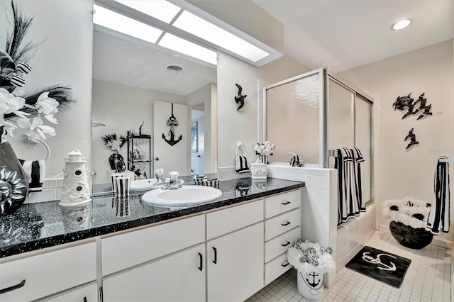 bathroom with vanity, a shower with door, a skylight, and tile patterned floors