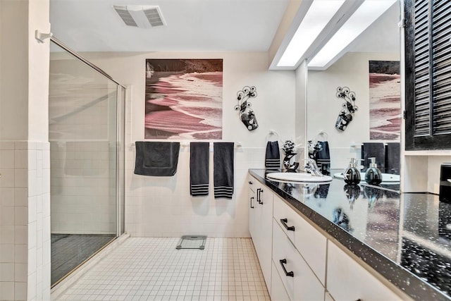 bathroom with vanity, tile walls, tile patterned floors, and a shower with shower door