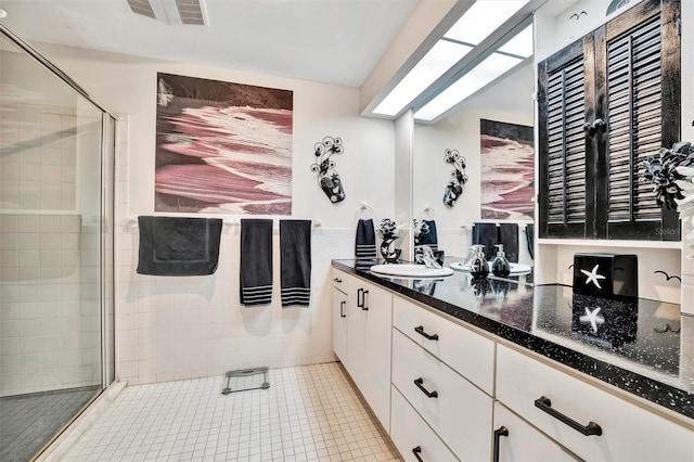 bathroom featuring vanity, tile patterned flooring, a shower with shower door, and tile walls