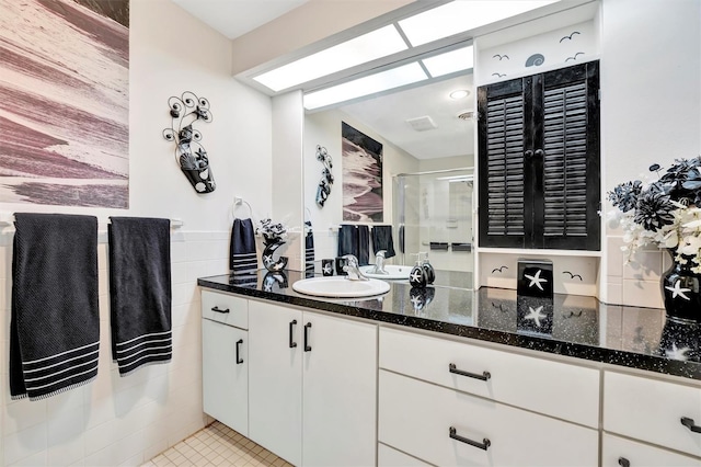 bathroom with vanity, tile walls, tile patterned floors, and a shower with shower door