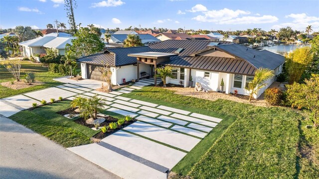 view of front of property featuring a water view, a garage, and a front lawn