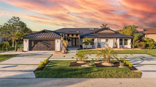 view of front facade featuring metal roof, a standing seam roof, an attached garage, and stucco siding