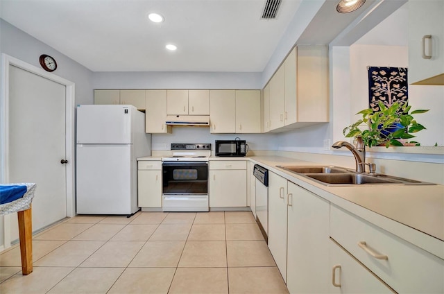 kitchen featuring sink, white appliances, cream cabinetry, and light tile patterned floors