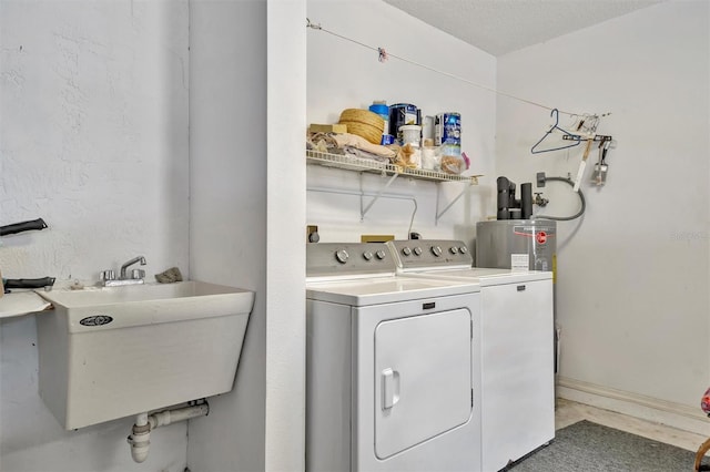 laundry area featuring electric water heater, sink, a textured ceiling, and independent washer and dryer