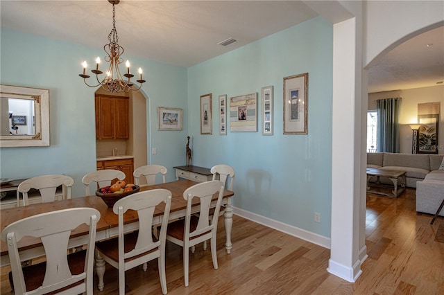 dining area with sink, a chandelier, and light wood-type flooring