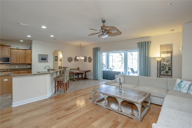 living room with sink, light hardwood / wood-style floors, and ceiling fan