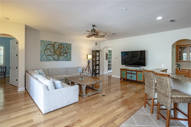 living room featuring sink, a textured ceiling, light hardwood / wood-style floors, and ceiling fan