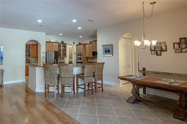 kitchen featuring stainless steel fridge, kitchen peninsula, stone counters, and a breakfast bar