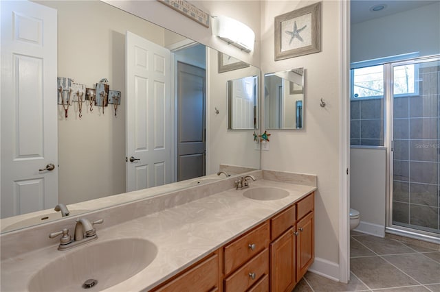 bathroom featuring tile patterned flooring, vanity, a shower with door, and toilet