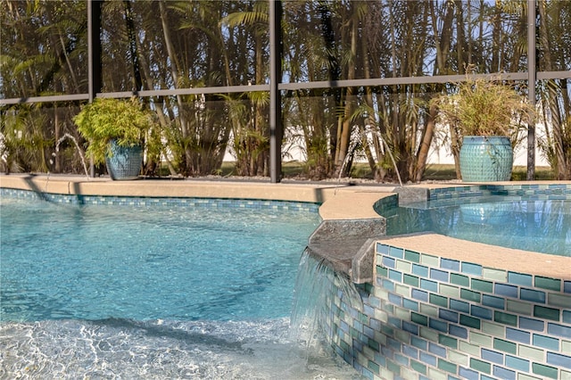 view of swimming pool featuring pool water feature and glass enclosure