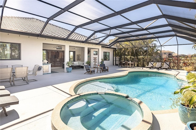 view of swimming pool with an in ground hot tub, a lanai, ceiling fan, and a patio area