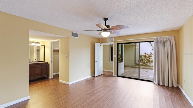 empty room with ceiling fan, sink, hardwood / wood-style floors, and a textured ceiling