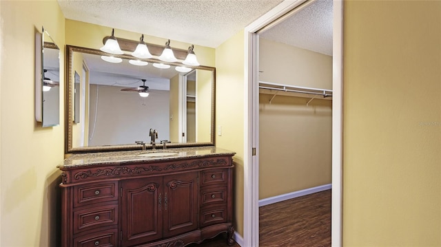 bathroom with hardwood / wood-style flooring, vanity, ceiling fan, and a textured ceiling