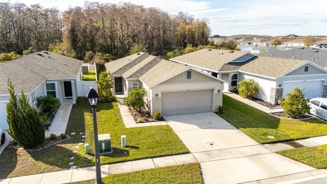 ranch-style house with a garage, concrete driveway, a residential view, a front lawn, and board and batten siding