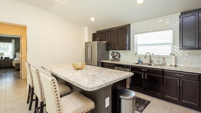 kitchen with a breakfast bar, lofted ceiling, light countertops, appliances with stainless steel finishes, and a kitchen island