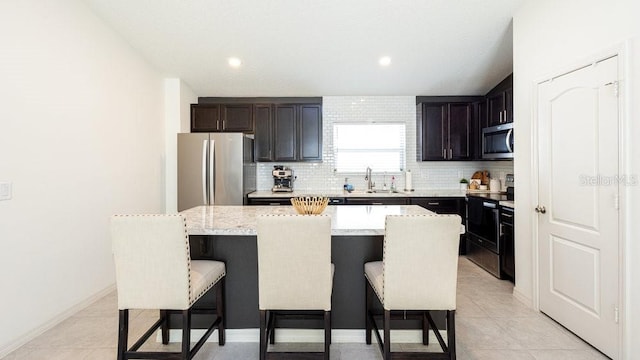 kitchen with appliances with stainless steel finishes, a kitchen island, a kitchen bar, and tasteful backsplash