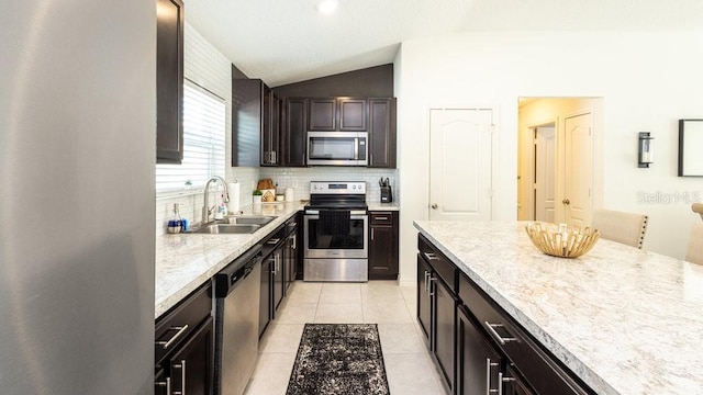 kitchen featuring stainless steel appliances, decorative backsplash, light tile patterned flooring, vaulted ceiling, and a sink