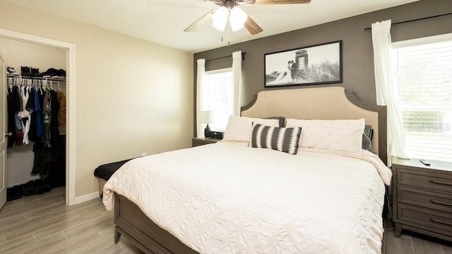 bedroom featuring baseboards, ceiling fan, a spacious closet, light wood-type flooring, and a closet