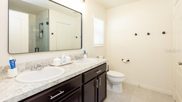 bathroom featuring double vanity, a stall shower, a sink, and baseboards