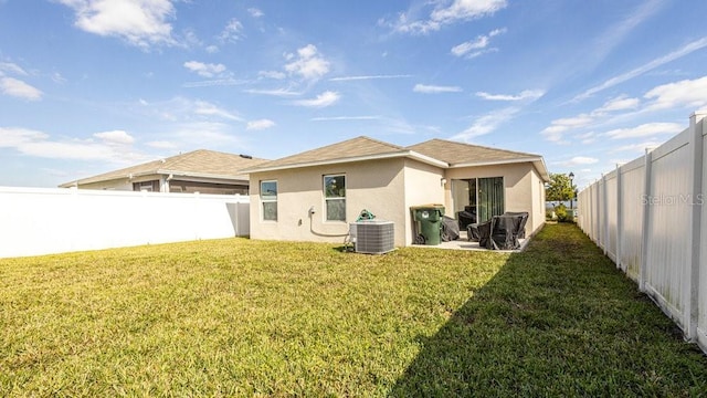 back of property featuring central air condition unit, a yard, a fenced backyard, and stucco siding