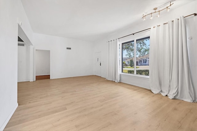 empty room with rail lighting and light hardwood / wood-style floors