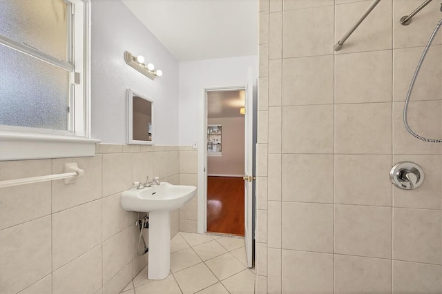 bathroom featuring tile patterned flooring, a tile shower, sink, and tile walls