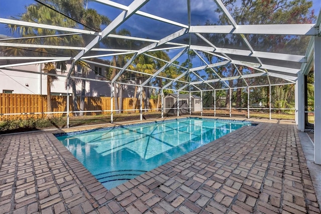 view of pool featuring a storage unit, a patio, and glass enclosure