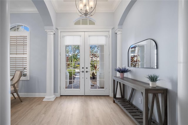 foyer with light hardwood / wood-style flooring, ornamental molding, french doors, and ornate columns