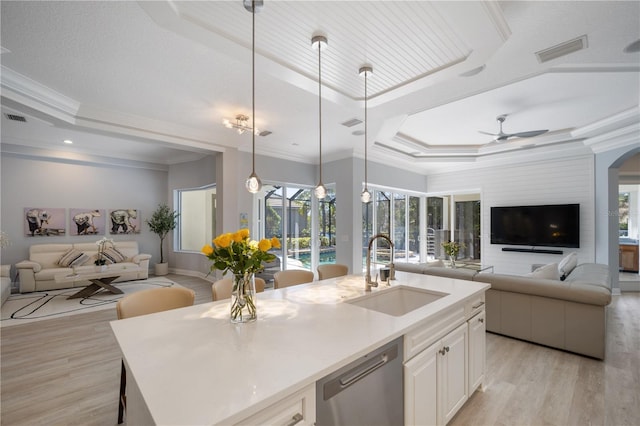 kitchen with dishwasher, a tray ceiling, open floor plan, and a sink