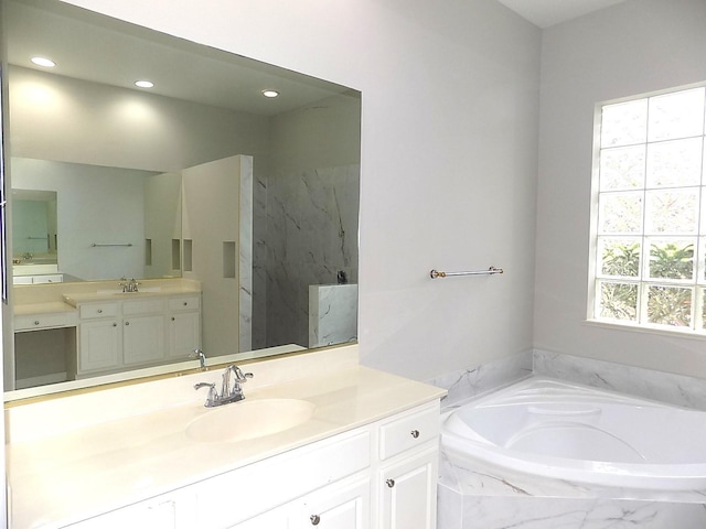 bathroom featuring vanity and tiled bath