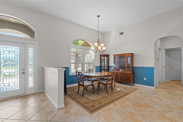 dining room with baseboards, visible vents, arched walkways, vaulted ceiling, and a notable chandelier