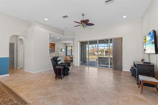 living area featuring arched walkways, recessed lighting, visible vents, and a ceiling fan