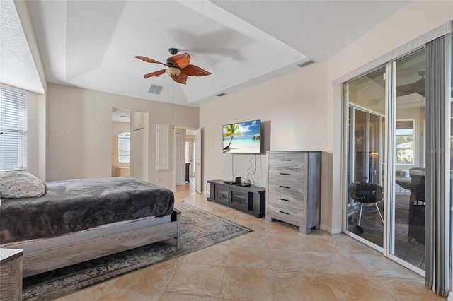 bedroom featuring access to exterior, visible vents, multiple windows, and a tray ceiling